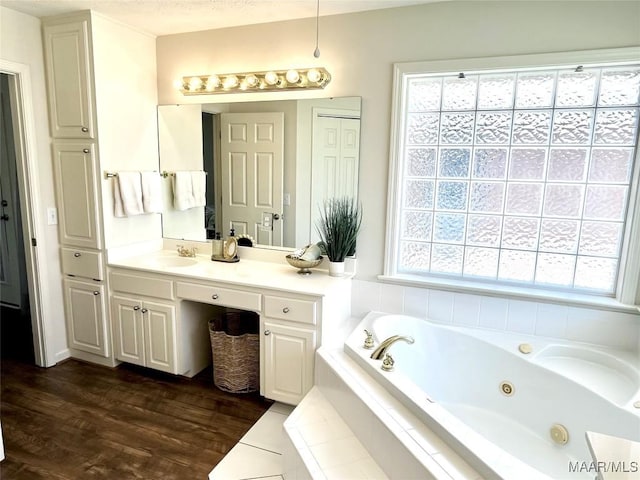 full bathroom with a jetted tub, vanity, and wood finished floors