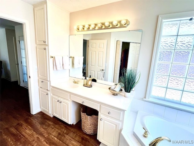 bathroom with wood finished floors, a bath, and vanity