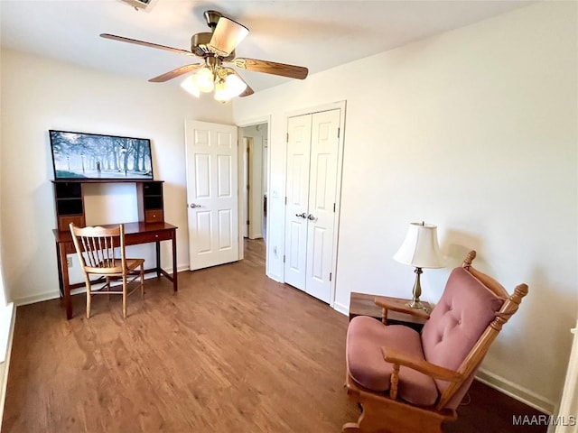 sitting room featuring wood finished floors, baseboards, a ceiling fan, and an office area