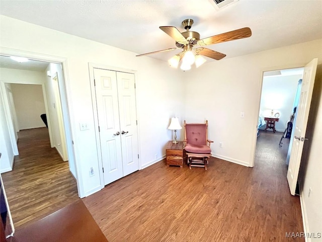 living area with wood finished floors, a ceiling fan, and baseboards