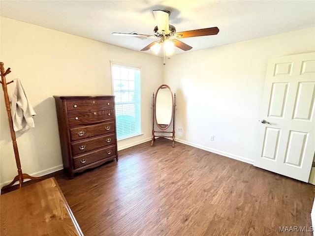 unfurnished bedroom featuring dark wood-type flooring, baseboards, and ceiling fan
