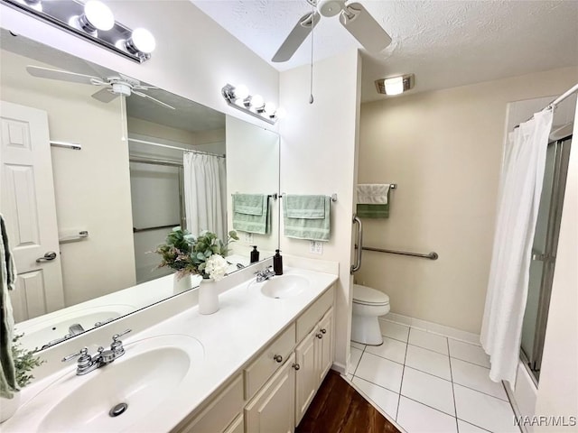 bathroom with ceiling fan, toilet, a shower with curtain, and a textured ceiling