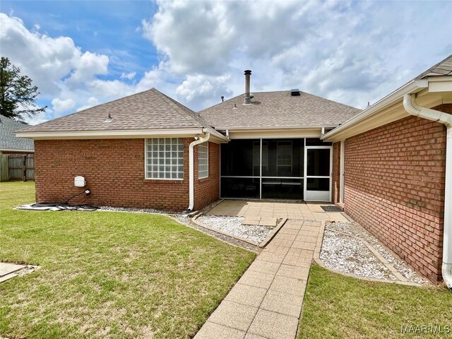 back of house with brick siding, roof with shingles, a patio, and a sunroom