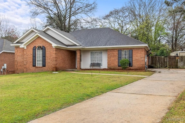 single story home featuring brick siding, roof with shingles, a front lawn, and fence