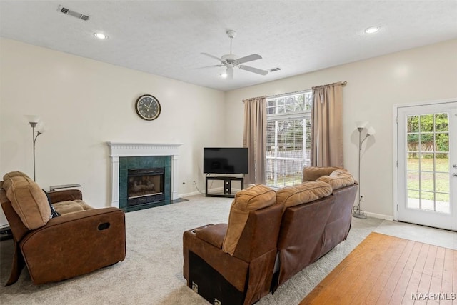 living room with a ceiling fan, a fireplace, visible vents, and baseboards