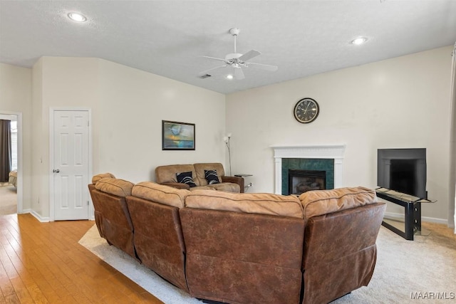 living room with a ceiling fan, a fireplace, light wood-style floors, and baseboards