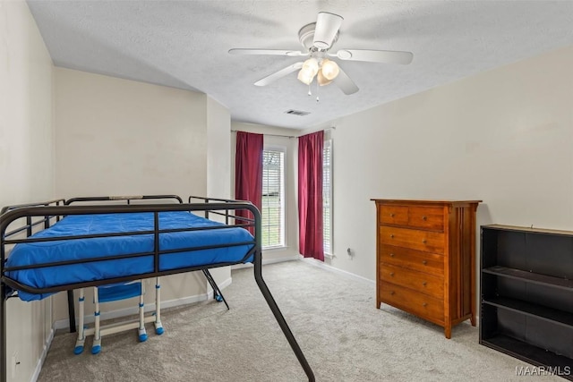 bedroom featuring baseboards, visible vents, ceiling fan, a textured ceiling, and carpet flooring