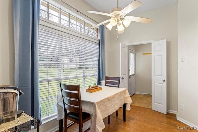 dining room with a wealth of natural light, baseboards, light wood-style floors, and a ceiling fan