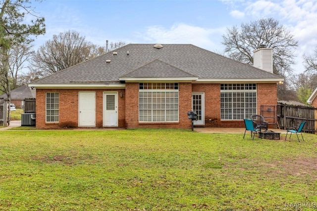 rear view of house with fence, an outdoor fire pit, a yard, central air condition unit, and brick siding