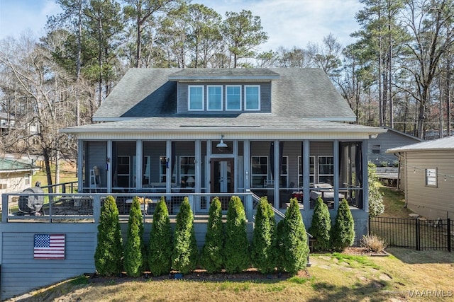 view of front of home featuring fence, roof with shingles, and a sunroom