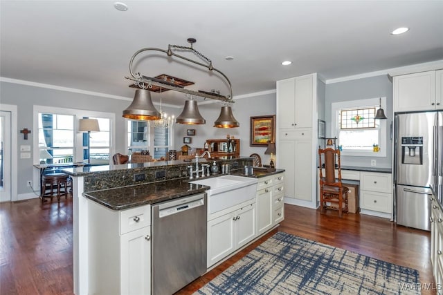 kitchen with dark wood-style floors, a sink, ornamental molding, stainless steel appliances, and white cabinets