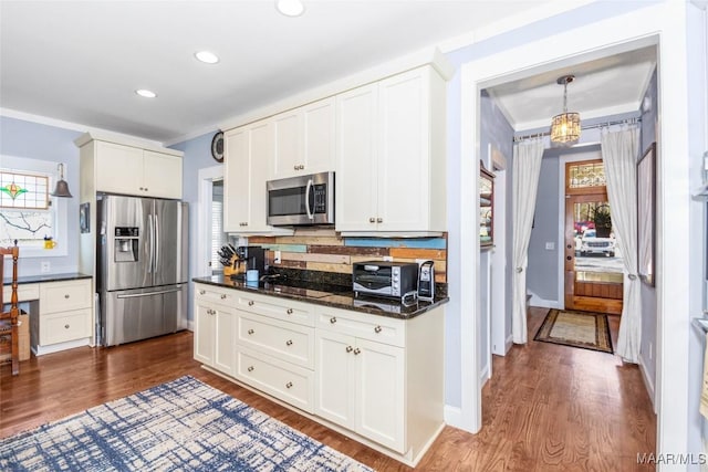 kitchen featuring dark countertops, dark wood finished floors, appliances with stainless steel finishes, and white cabinetry