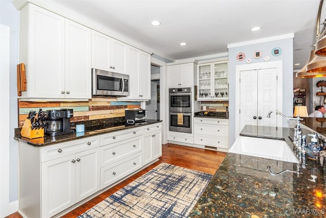 kitchen with glass insert cabinets, wood finished floors, white cabinets, stainless steel appliances, and a sink