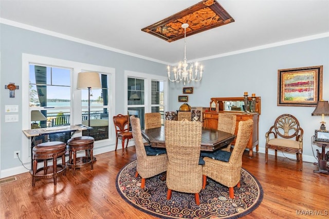 dining area featuring visible vents, wood finished floors, a chandelier, and crown molding