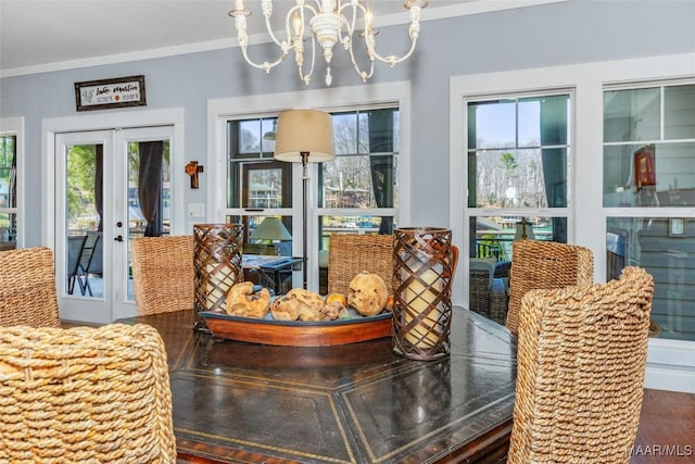 dining space with a chandelier, wood finished floors, ornamental molding, and french doors