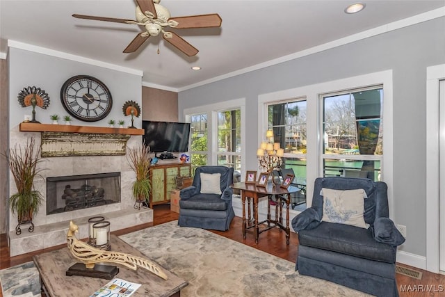 living room with crown molding, baseboards, a premium fireplace, recessed lighting, and wood finished floors