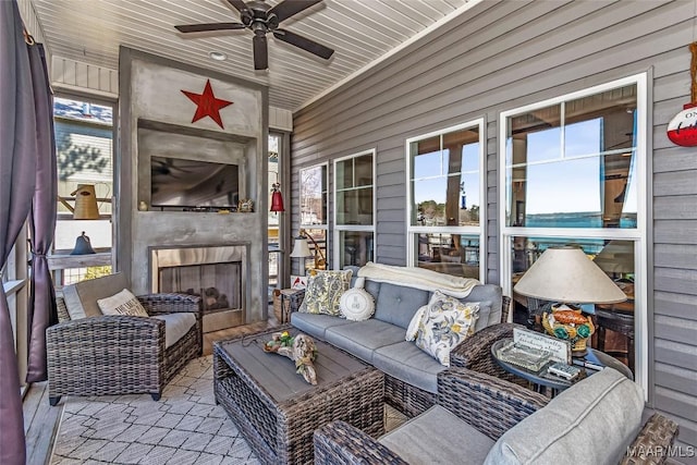 sunroom / solarium with wood ceiling, ceiling fan, and a tile fireplace