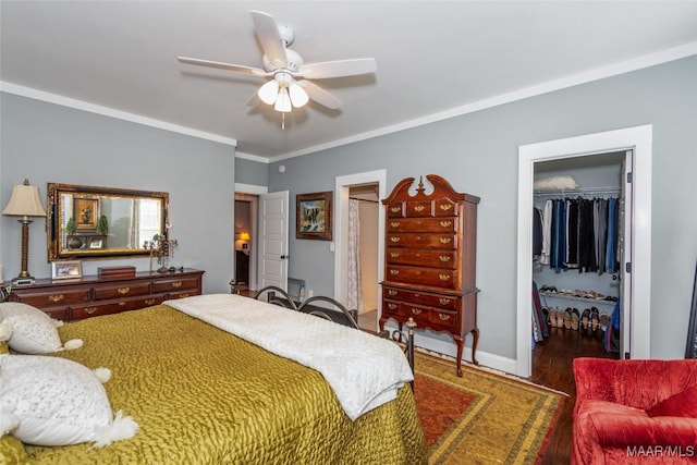 bedroom with a spacious closet, baseboards, ornamental molding, wood finished floors, and a closet