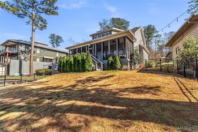 rear view of house with stairway, fence, a yard, and a sunroom