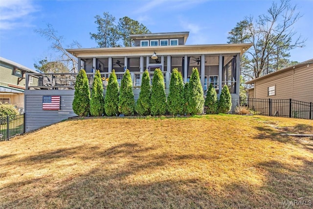 back of house with fence, a lawn, and a sunroom