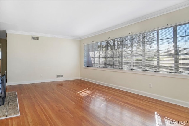 unfurnished living room featuring visible vents, crown molding, baseboards, and wood finished floors