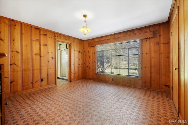 spare room with tile patterned floors, wooden walls, and baseboards