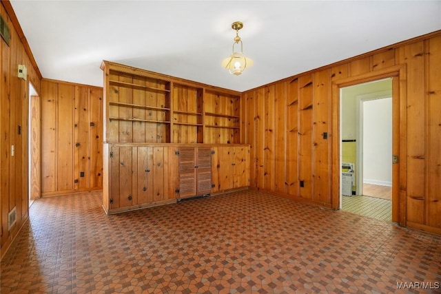 unfurnished room with tile patterned floors, visible vents, wood walls, and ornamental molding