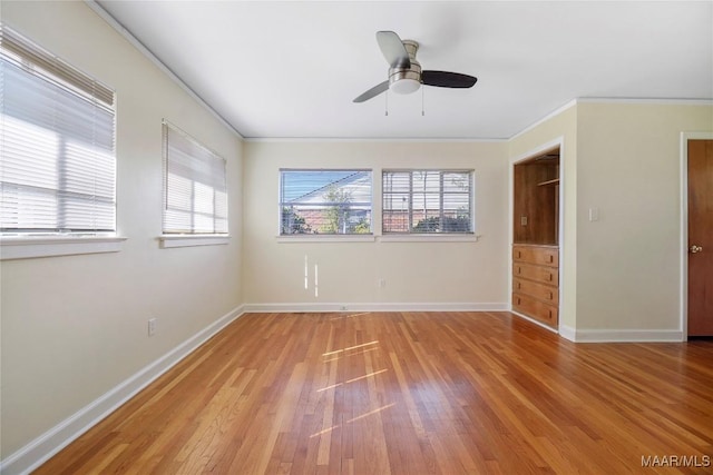 empty room featuring a ceiling fan, baseboards, light wood-style floors, and crown molding