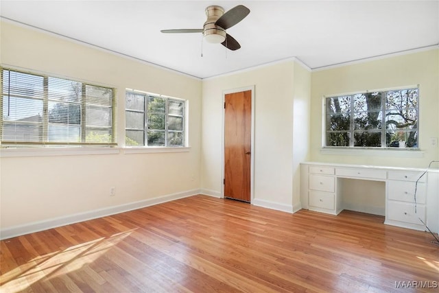 unfurnished bedroom featuring baseboards, light wood-style floors, crown molding, and built in study area