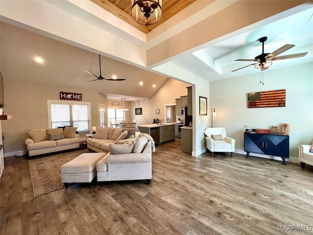 living room featuring dark wood finished floors, a raised ceiling, a ceiling fan, and baseboards