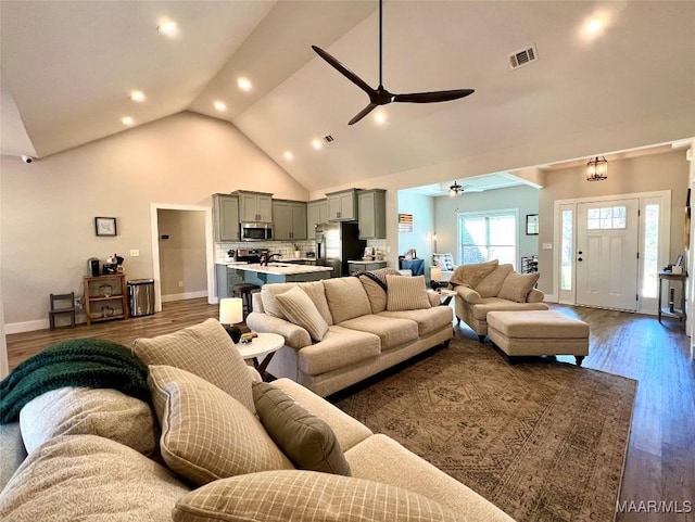 living area featuring visible vents, high vaulted ceiling, wood finished floors, baseboards, and ceiling fan