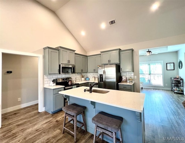 kitchen with a sink, stainless steel appliances, backsplash, and gray cabinets