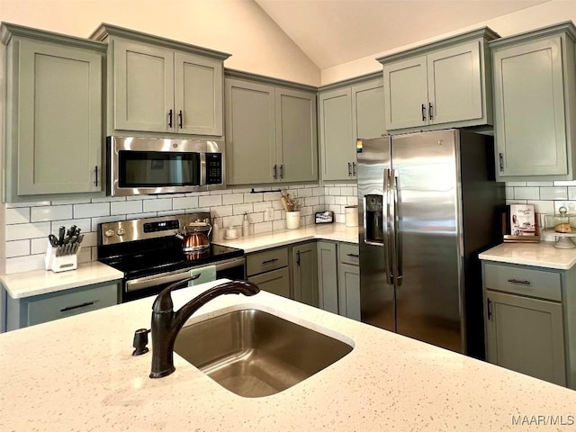 kitchen featuring a sink, lofted ceiling, gray cabinets, and stainless steel appliances