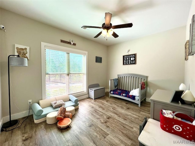 bedroom featuring baseboards, wood finished floors, and a ceiling fan