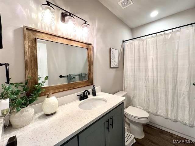 bathroom with visible vents, toilet, shower / bath combo, wood finished floors, and vanity