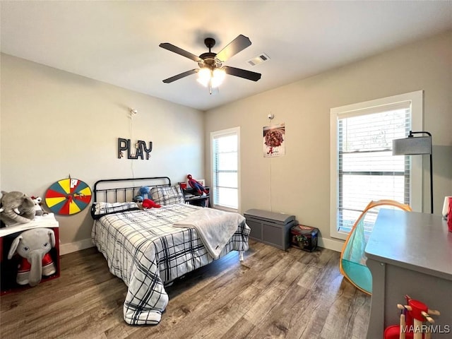 bedroom featuring ceiling fan, visible vents, baseboards, and wood finished floors