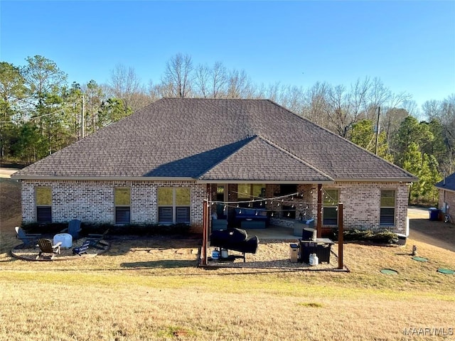 rear view of house featuring a yard, brick siding, and roof with shingles