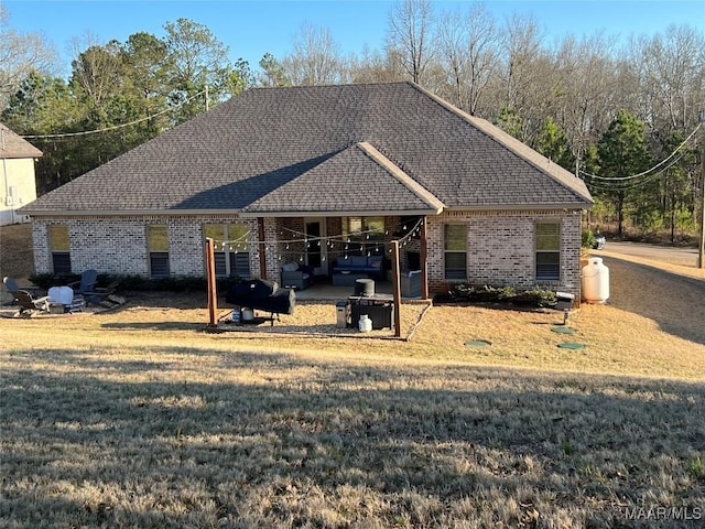 view of front of property with a patio area, a front yard, brick siding, and a shingled roof