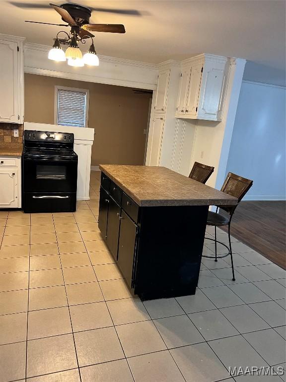 kitchen with white cabinetry, dark countertops, black electric range, and light tile patterned floors