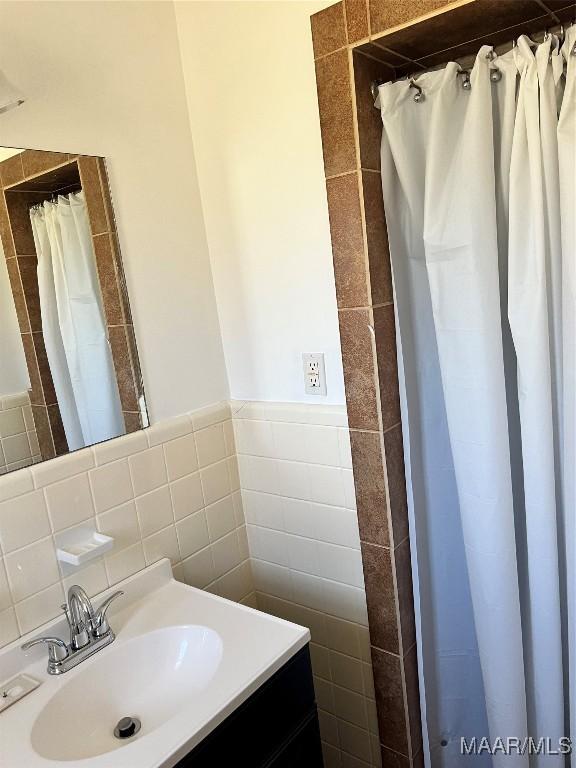 bathroom featuring curtained shower, tile walls, and vanity