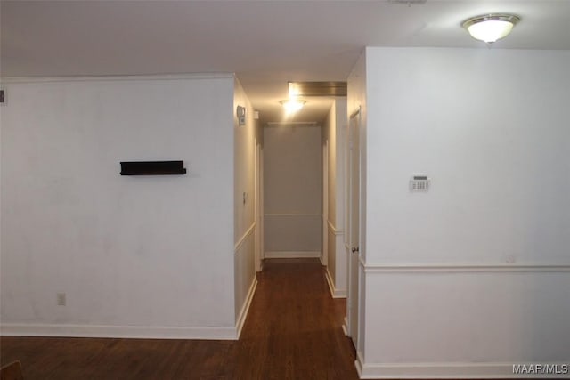 corridor featuring dark wood-type flooring and baseboards