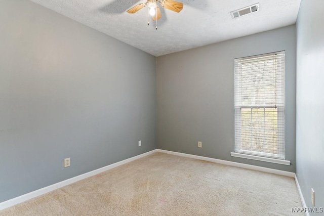 unfurnished room featuring a ceiling fan, carpet, visible vents, and a textured ceiling