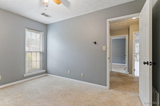 spare room with baseboards, visible vents, a textured ceiling, and carpet