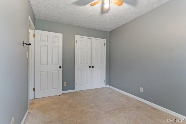 unfurnished bedroom with a closet, baseboards, a textured ceiling, and carpet flooring