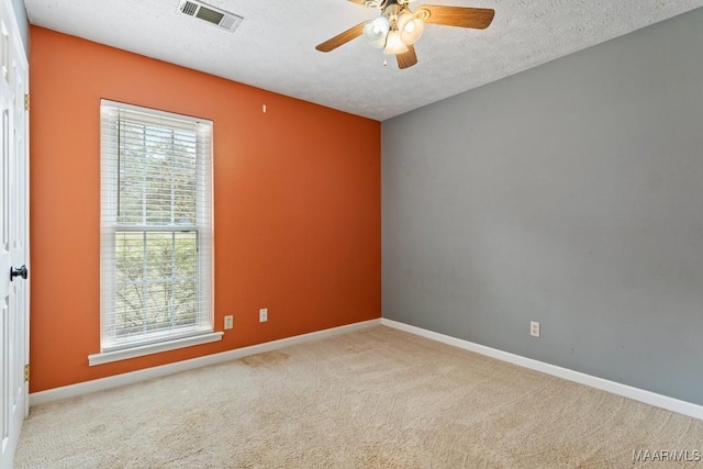 carpeted spare room with visible vents, baseboards, and a textured ceiling