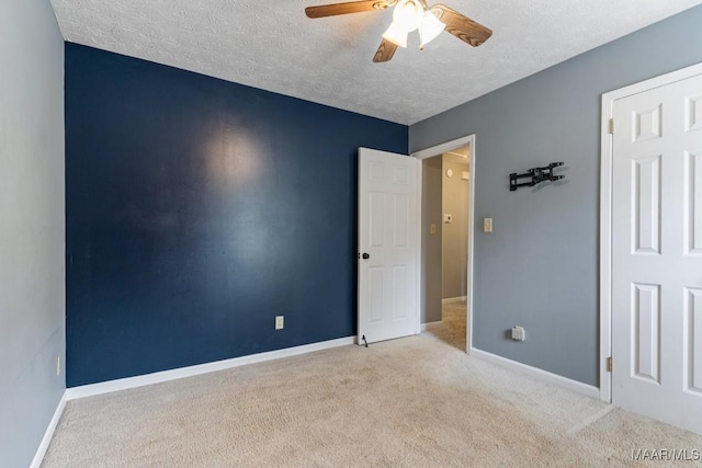 carpeted empty room with baseboards, a textured ceiling, and a ceiling fan