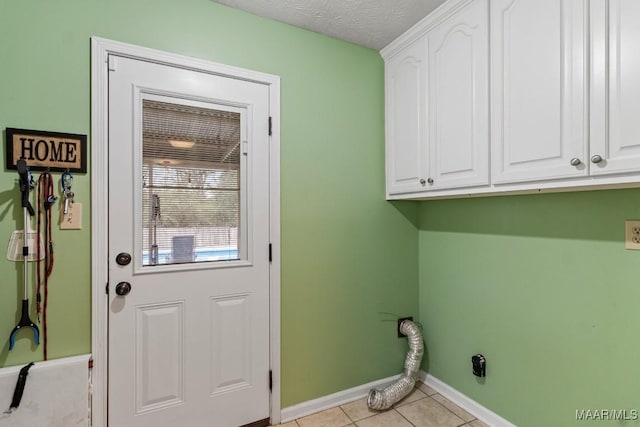 clothes washing area featuring light tile patterned floors, baseboards, cabinet space, and a textured ceiling