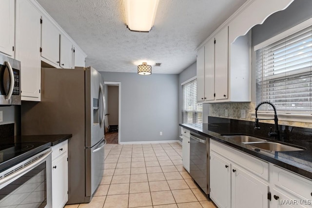 kitchen featuring light tile patterned floors, a sink, white cabinets, appliances with stainless steel finishes, and tasteful backsplash