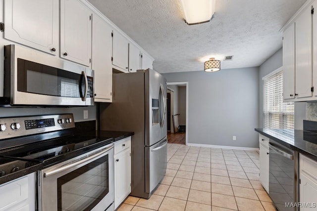 kitchen with dark countertops, visible vents, appliances with stainless steel finishes, and white cabinetry