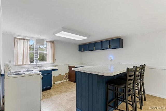 kitchen with white range with electric cooktop, a breakfast bar, light countertops, blue cabinets, and a sink